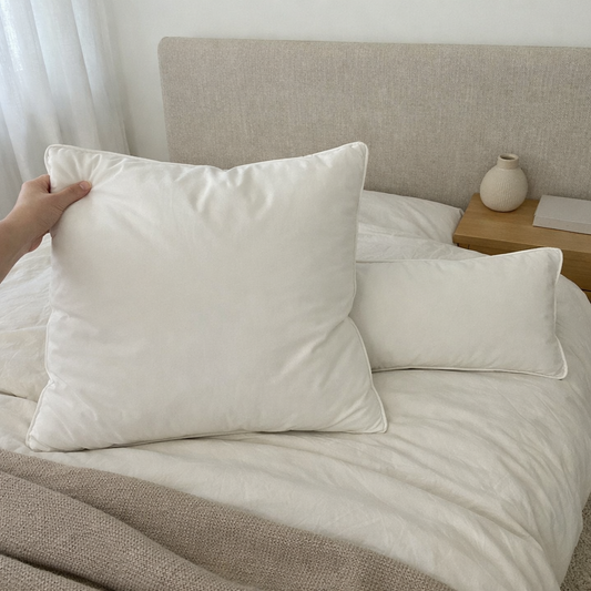 Kopfkissen 80x80 im Vordergrund auf einem Bett, daneben ein Kissen 40x80 als Größenvergleich